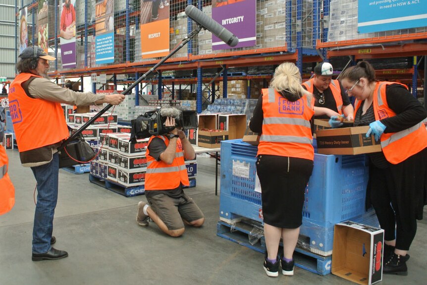 Carl Saville and Tony Hill wearing high vis vests while filming at Foodbank warehouse.