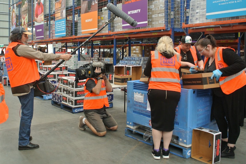 Carl Saville and Tony Hill wearing high vis vests while filming at Foodbank warehouse.