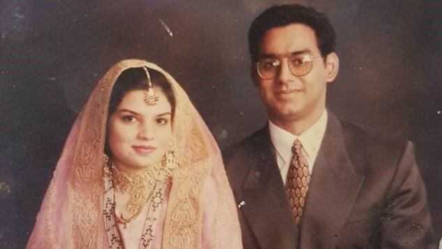 A man in a suit sits next to a woman in a traditional peach-coloured Pakistani sari and jewellery