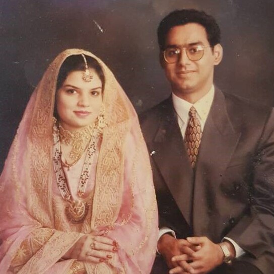 A man in a suit sits next to a woman in a traditional peach-coloured Pakistani sari and jewellery