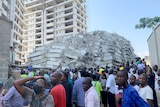 The huge pile of building rubble in background with a crowd in front