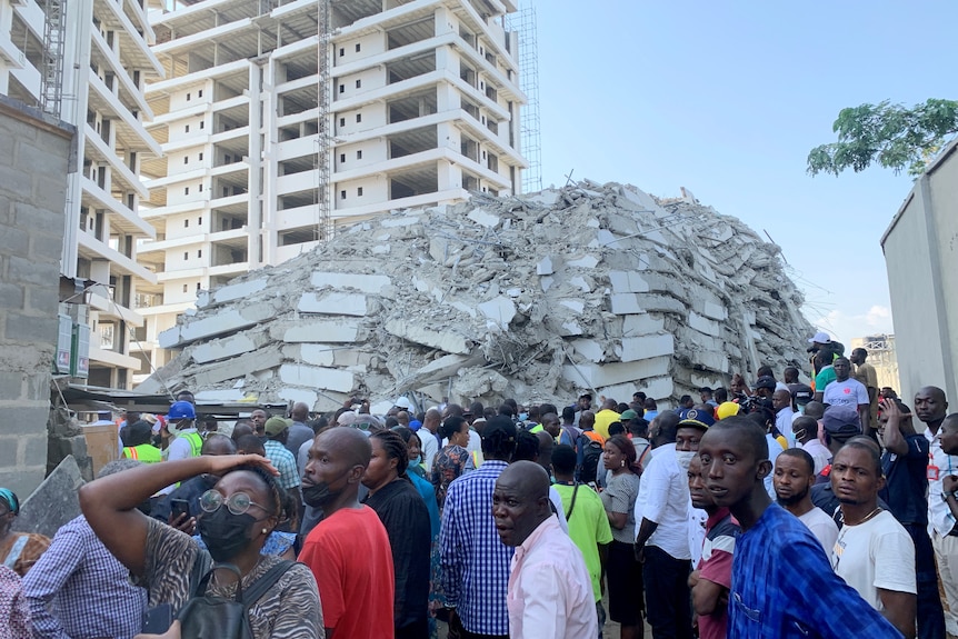 The huge pile of building rubble in background with a crowd in front