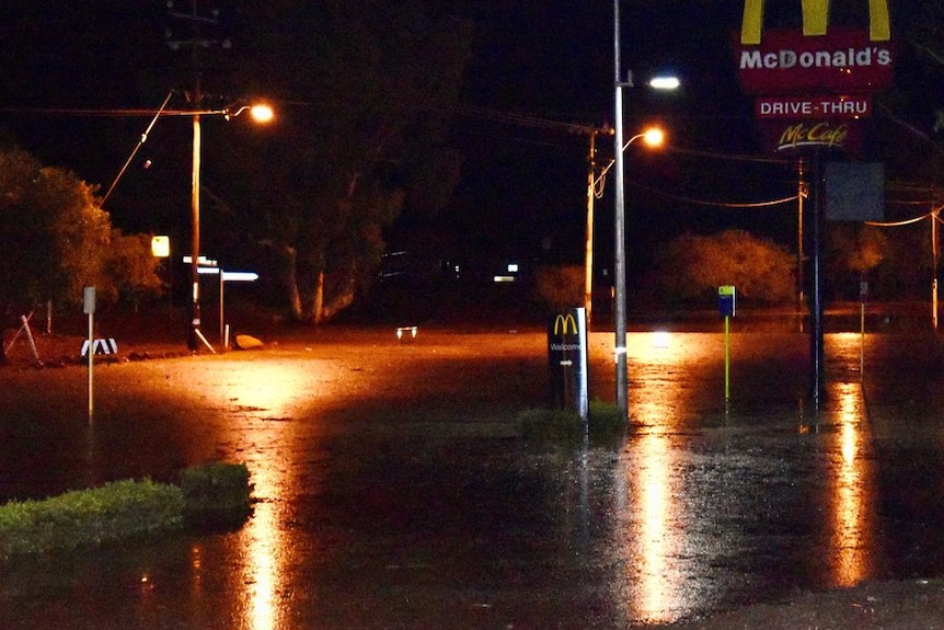 Street lights illuminate a flooded road in front of a fast food drive through.
