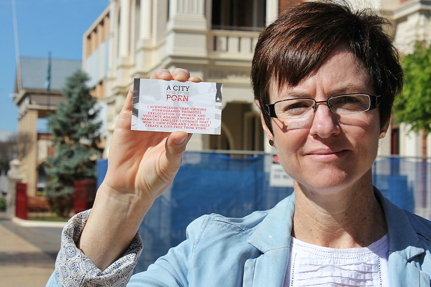 A woman holds a card with 'city free from porn' written on it
