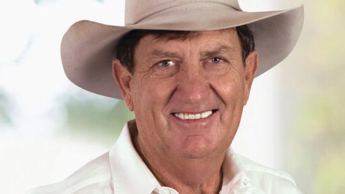 A man wearing a cowboy hat smiles at camera. 