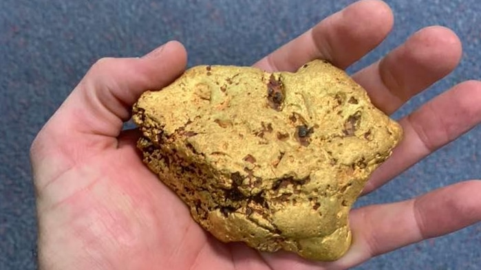A large gold nugget held in the palm of a man's hand.
