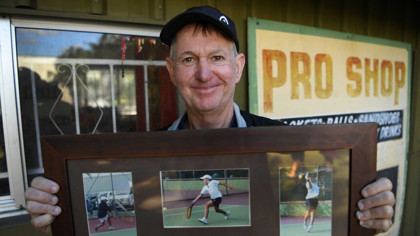 A tennis coach shows a poster featuring photos of Ash Barty playing tennis as a junior.