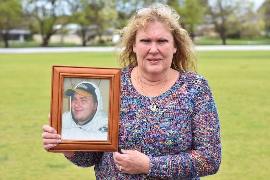 Woman holds picture of son.