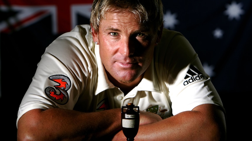 Shane Warne poses for a portrait in front of the Ashes urn and the Australian flag
