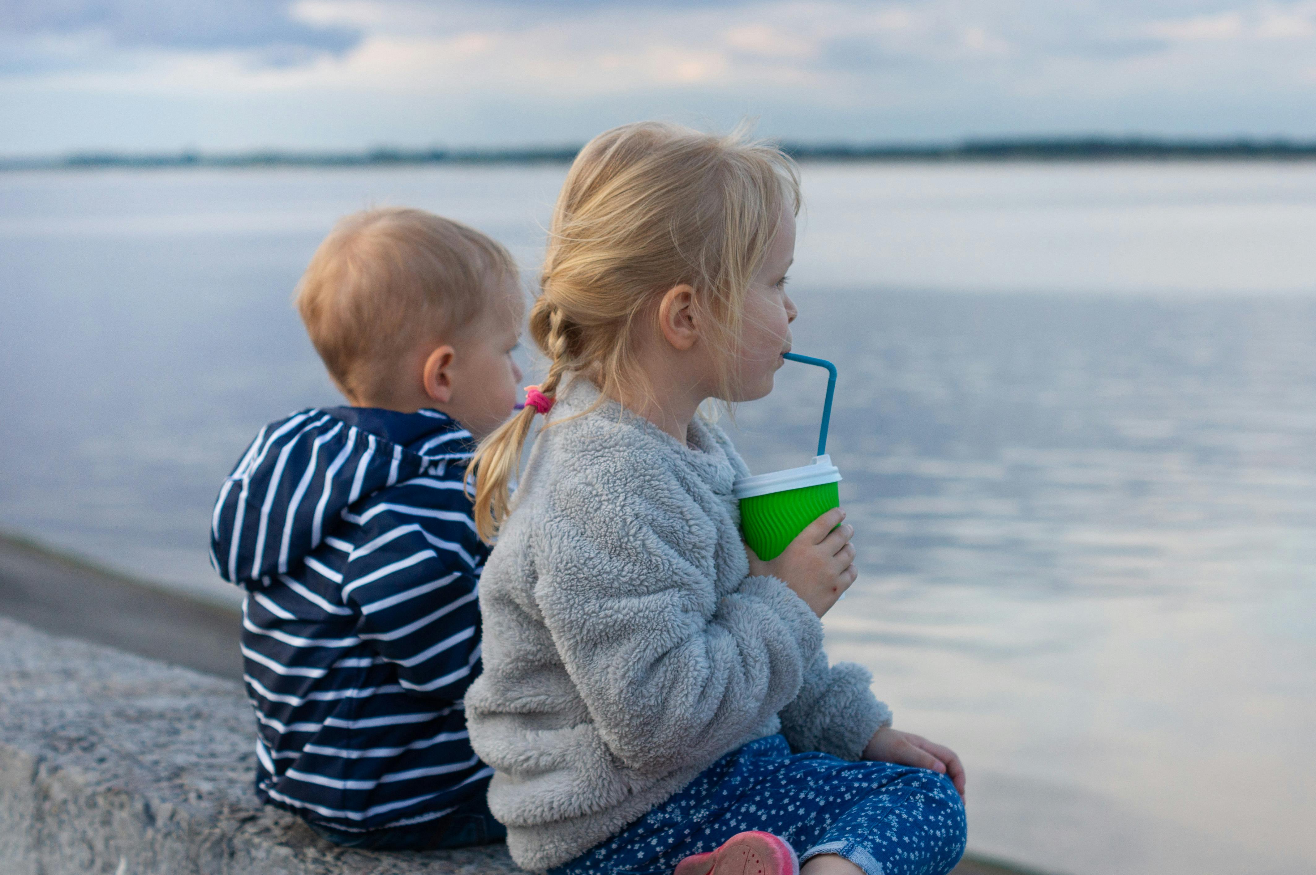 kids wearing warm clothes sitting by the water