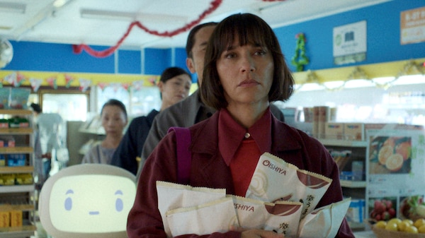 A woman stand in line at a grocery story in front of a white robot and other humans