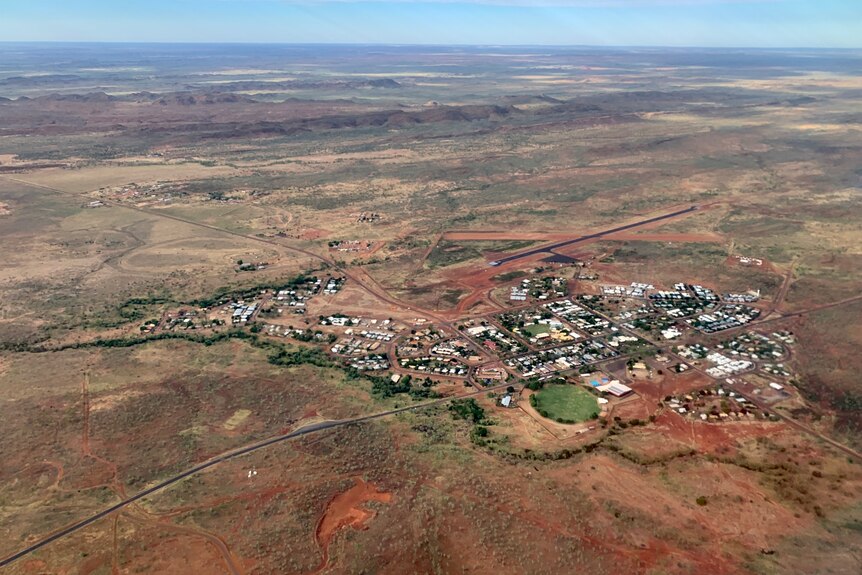 a small town surrounded by red dirt, and the green footy oval in foreground