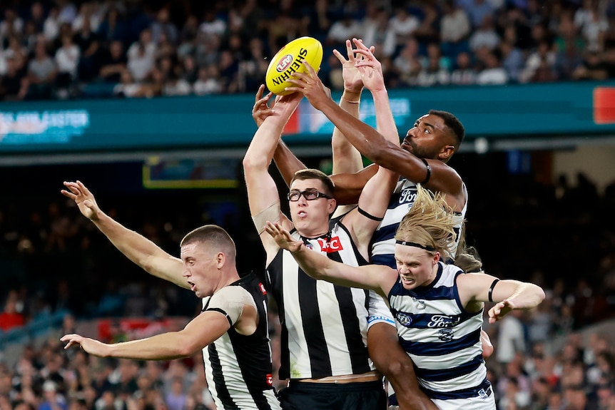 Mason Cox and Esava Ratugolea are at the front of a big pack of players trying to mark the ball
