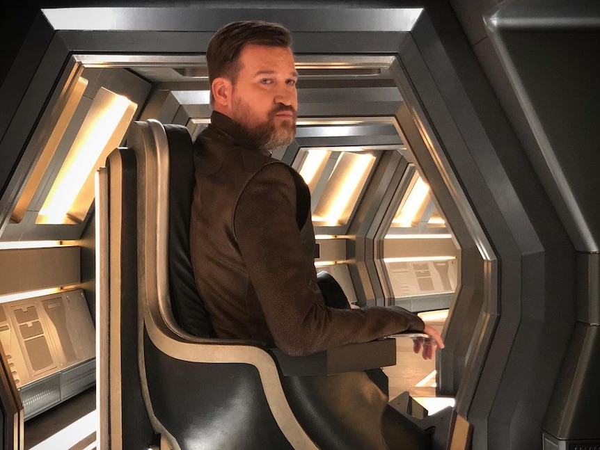 Actor Kenneth Mitchell sitting in a black wheelchair on the set of Star Trek Discovery
