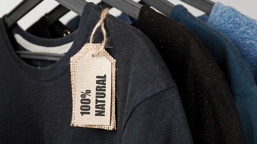A row of t-shirts on hangers, with a label reading '100% natural' hanging off one.