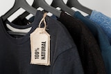 A row of t-shirts on hangers, with a label reading '100% natural' hanging off one.