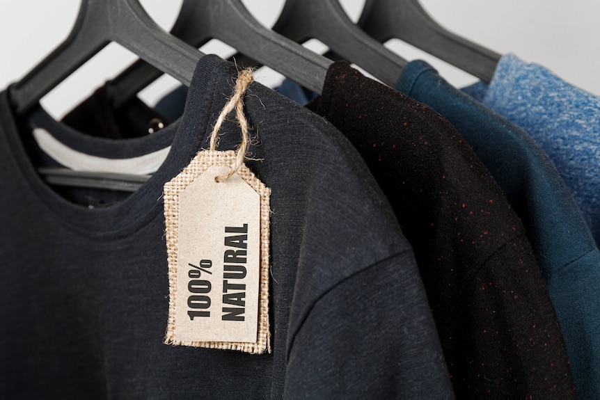 A row of t-shirts on hangers, with a label reading '100% natural' hanging off one.