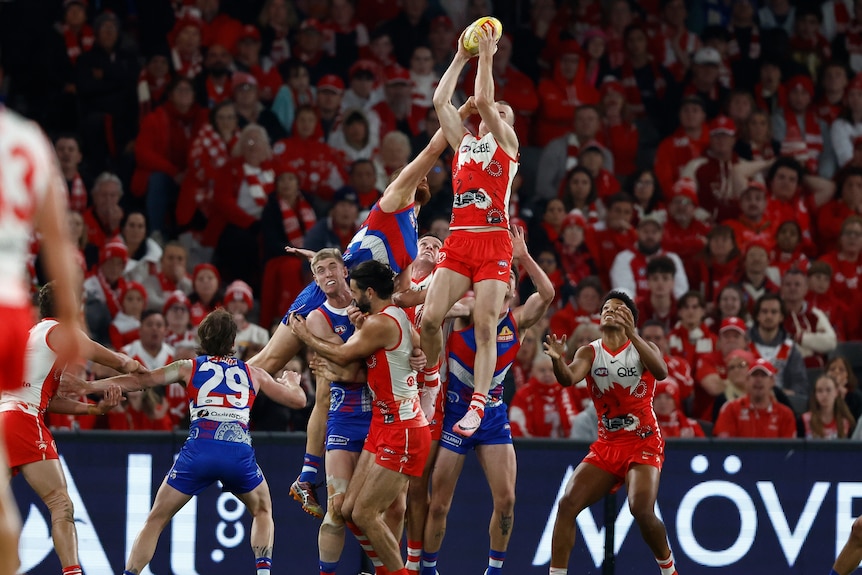 Chad Warner of the Sydney Swas takes a mark high above a pack of Western Bulldogs during an AFL game.