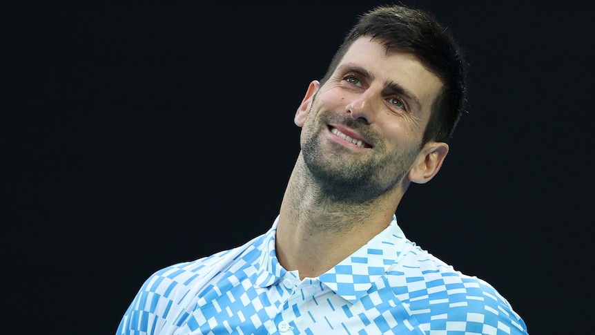 Novak Djokovic smiles as he tilts his head during an Australian Open match.