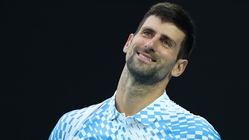 Novak Djokovic smiles as he tilts his head during an Australian Open match.