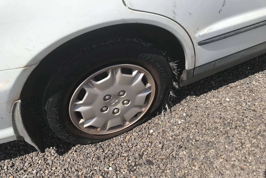 A flat tyre on a white car