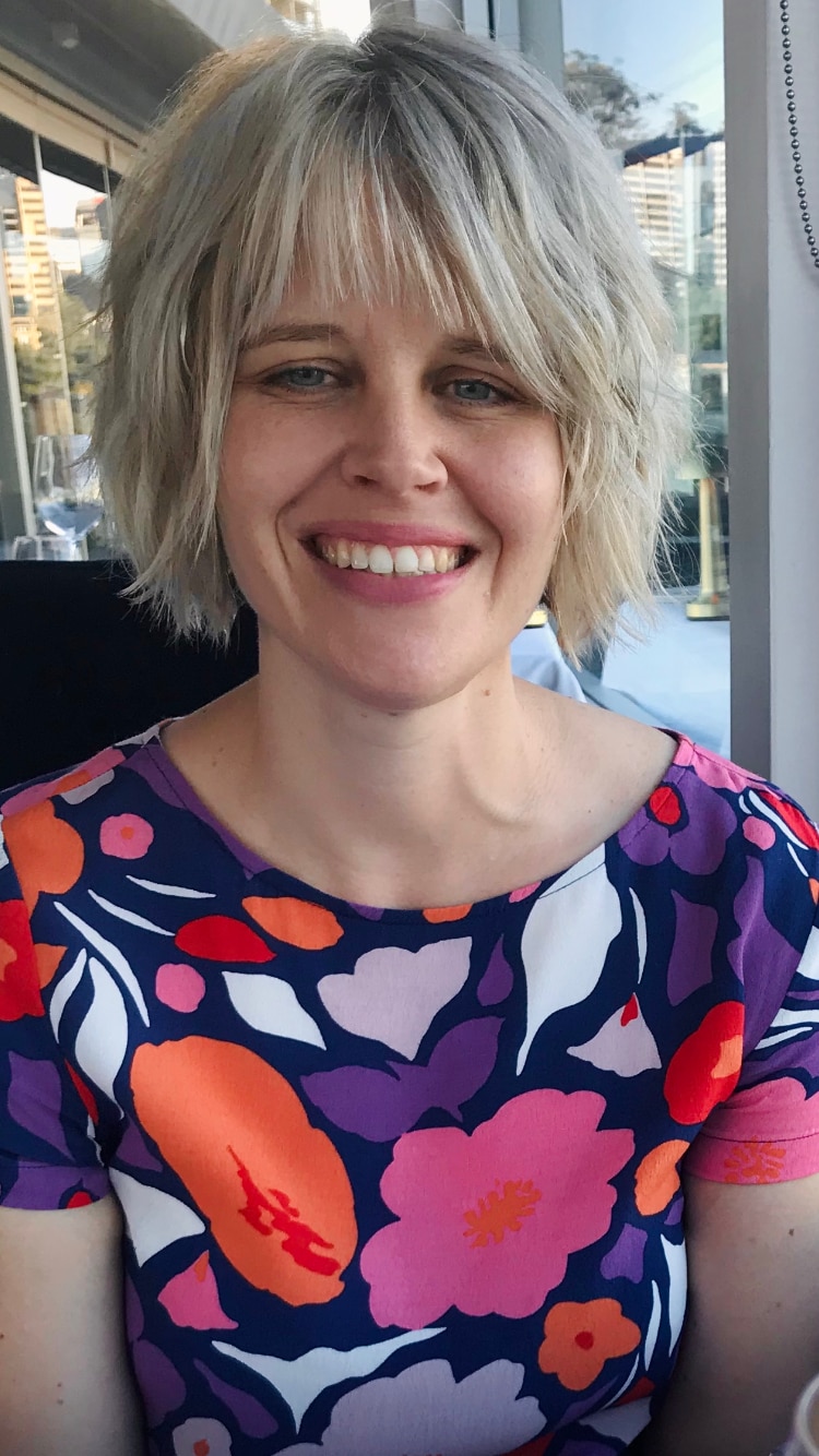 Dr Rachel Berry with a blond bob and wearing a pink and orange dotted shirt 