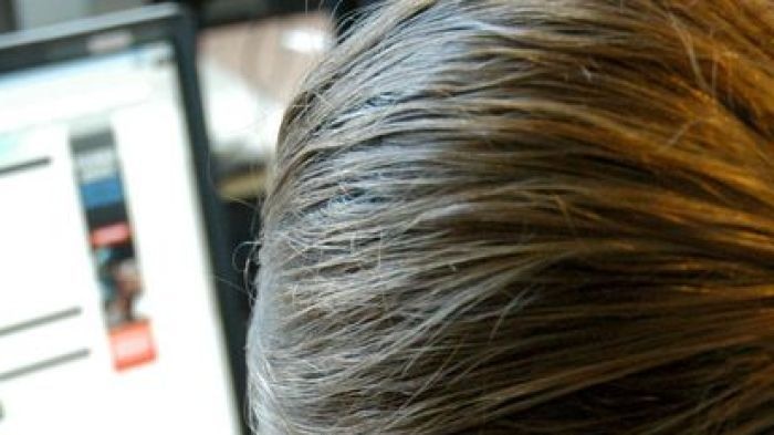 A woman photographed from behind while working on a computer.