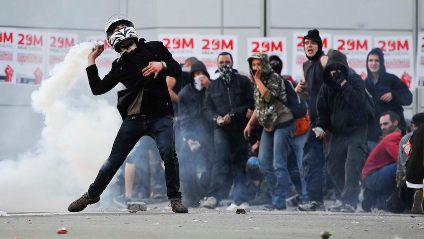 A demonstrator throws back a teargas canister during heavy clashes with riot police in Barcelona