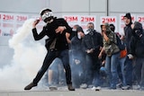 A demonstrator throws back a teargas canister during heavy clashes with riot police in Barcelona