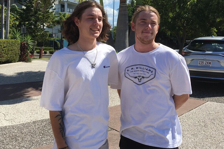 Two young men standing in white t-shirts.