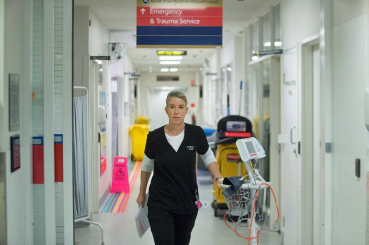 A woman walks down a hallway in a hospital.