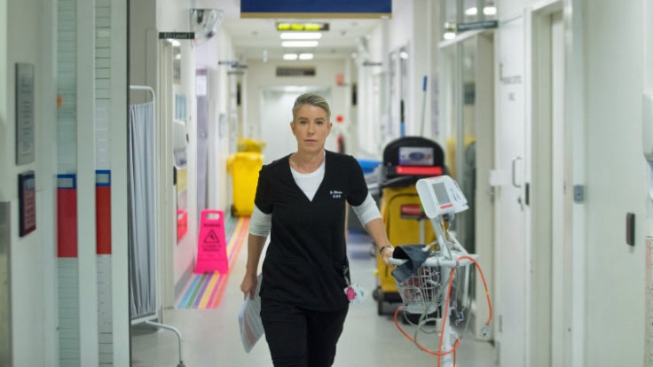 A woman walks down a hallway in a hospital.