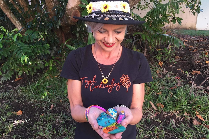 A woman holding painted stones in remembrance