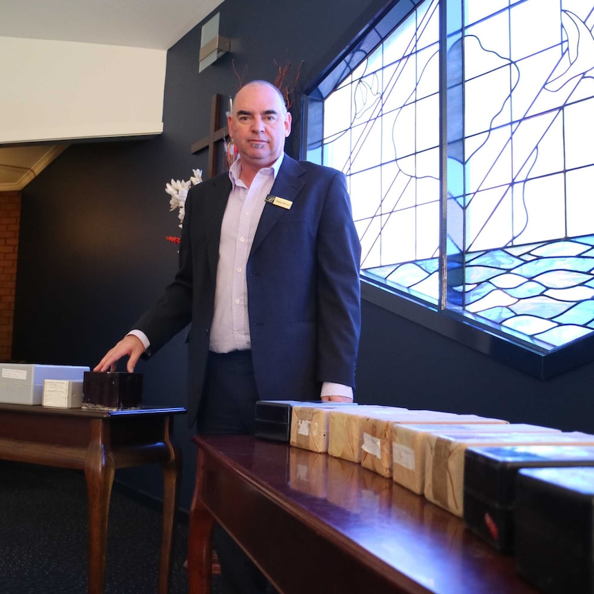 Funeral home manager Simon Dwyer standing in front a stained glass window