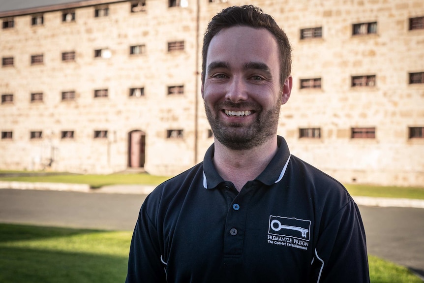 Man stands in front of limestone prison building