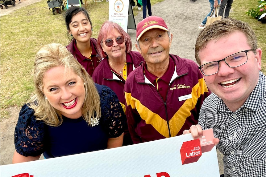 Three women and two men taking a selfie while holding up a sign of SA Labor Beach Road Revitalisation sign