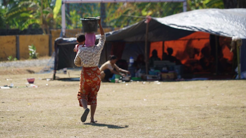 Woman carries bucket on her head in a camp for displaced people after the Lombok earthquakes