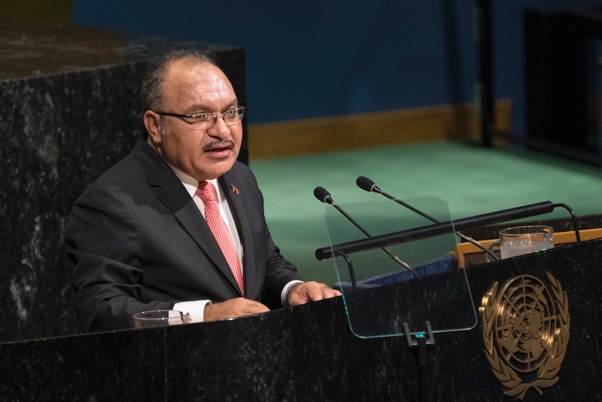 Peter O'Neill stands behind the black marble United Nations General Assembly lectern.