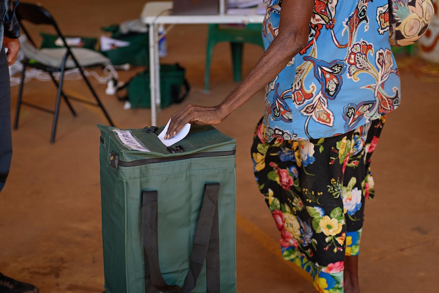 a woman casts a vote in a rural polling booth