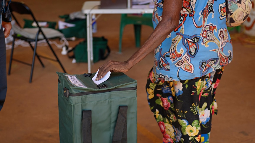 a woman casts a vote in a rural polling booth