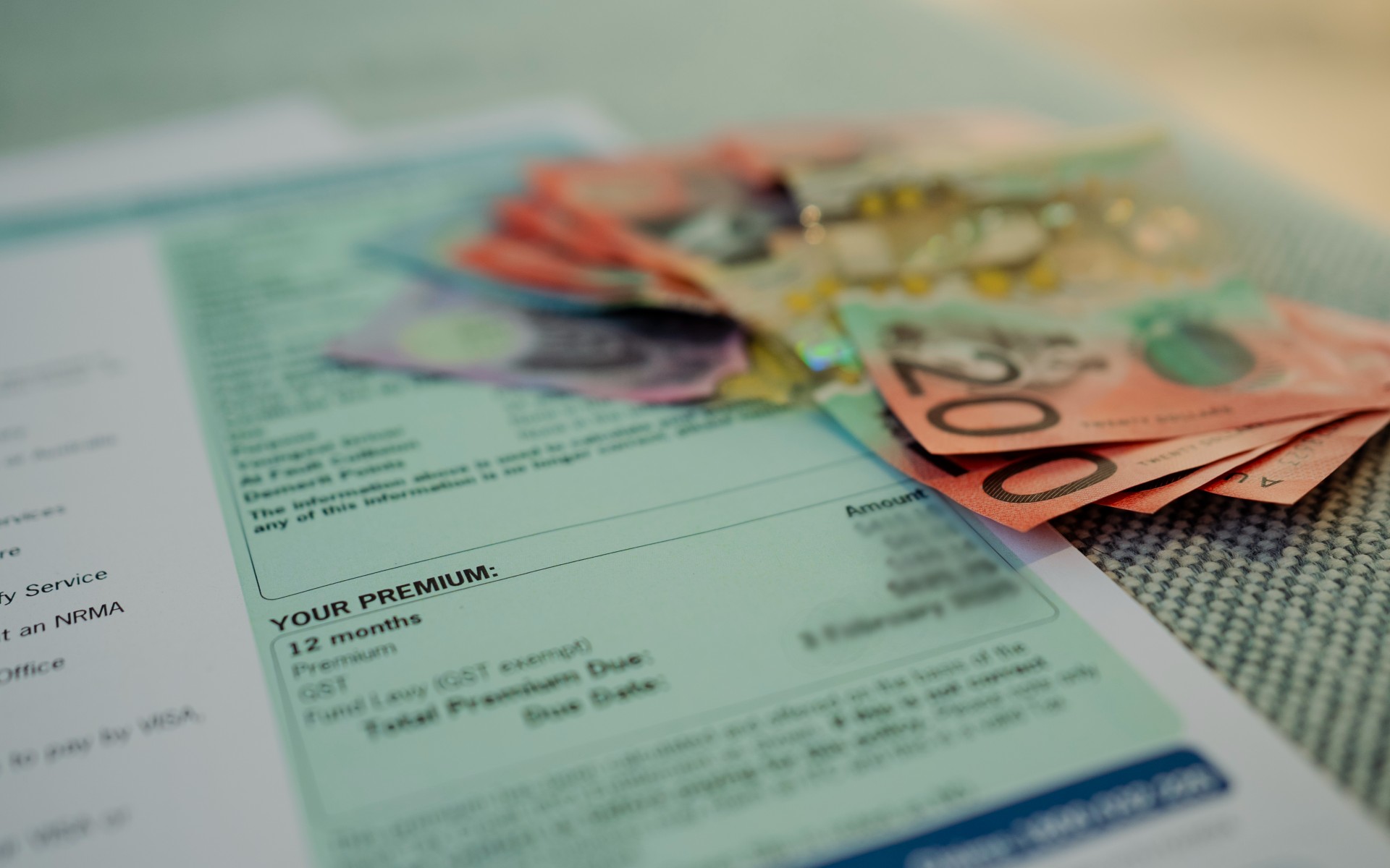 An up close of a fanned wad of cash, next to a greenslip document saying PREMIUM with blurred private details.