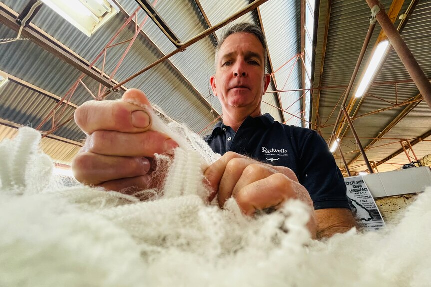 A man pulling on a piece of wool to test its strength