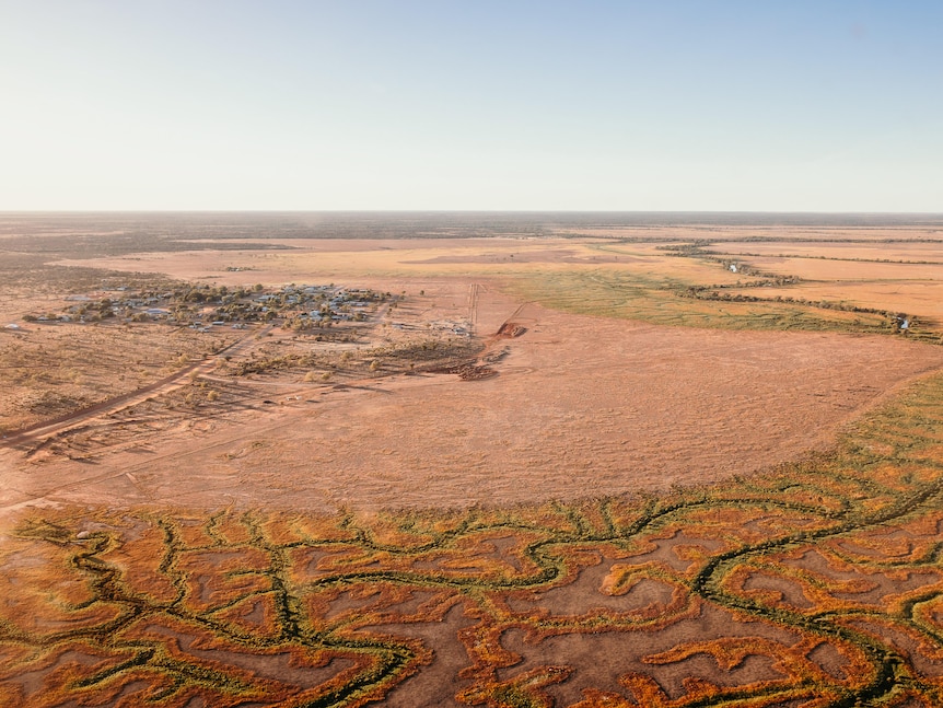 An aerial shot of a small town surrounded by green, yellow, and orange channels.