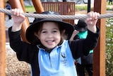 A young student hangs on to a rope in the playground.