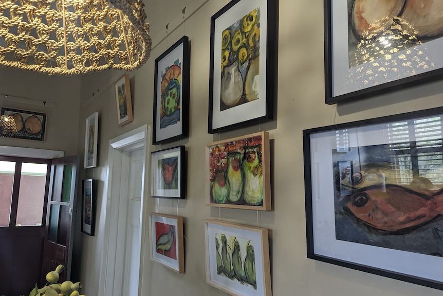 A hallway is filled with multiple watercolour paintings featuring bright and vibrant colours.