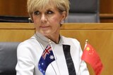 Julie Bishop sits with small Australian and Chinese flags in foreground.
