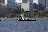 The torn-off tail of a sea plane is lifted from the Swan River by a crane on a barge.