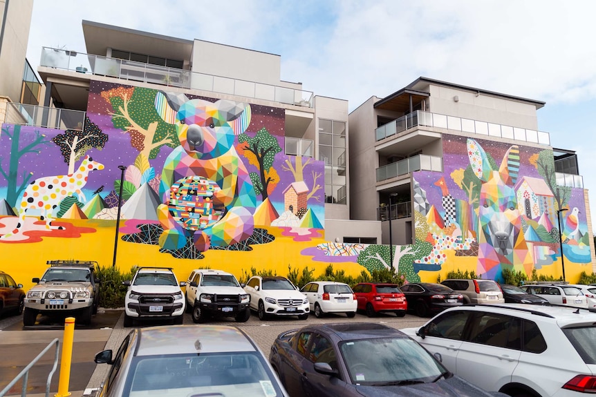 A mural on the wall of a building overlooking a carpark