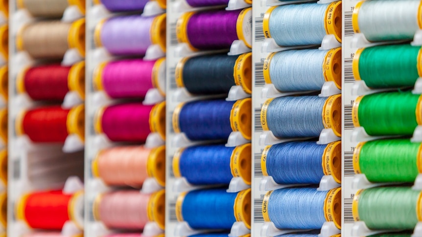 Uniform rows of brightly coloured cotton reels.
