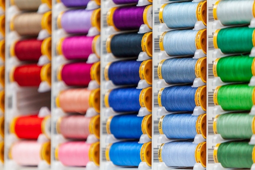 Uniform rows of brightly coloured cotton reels.